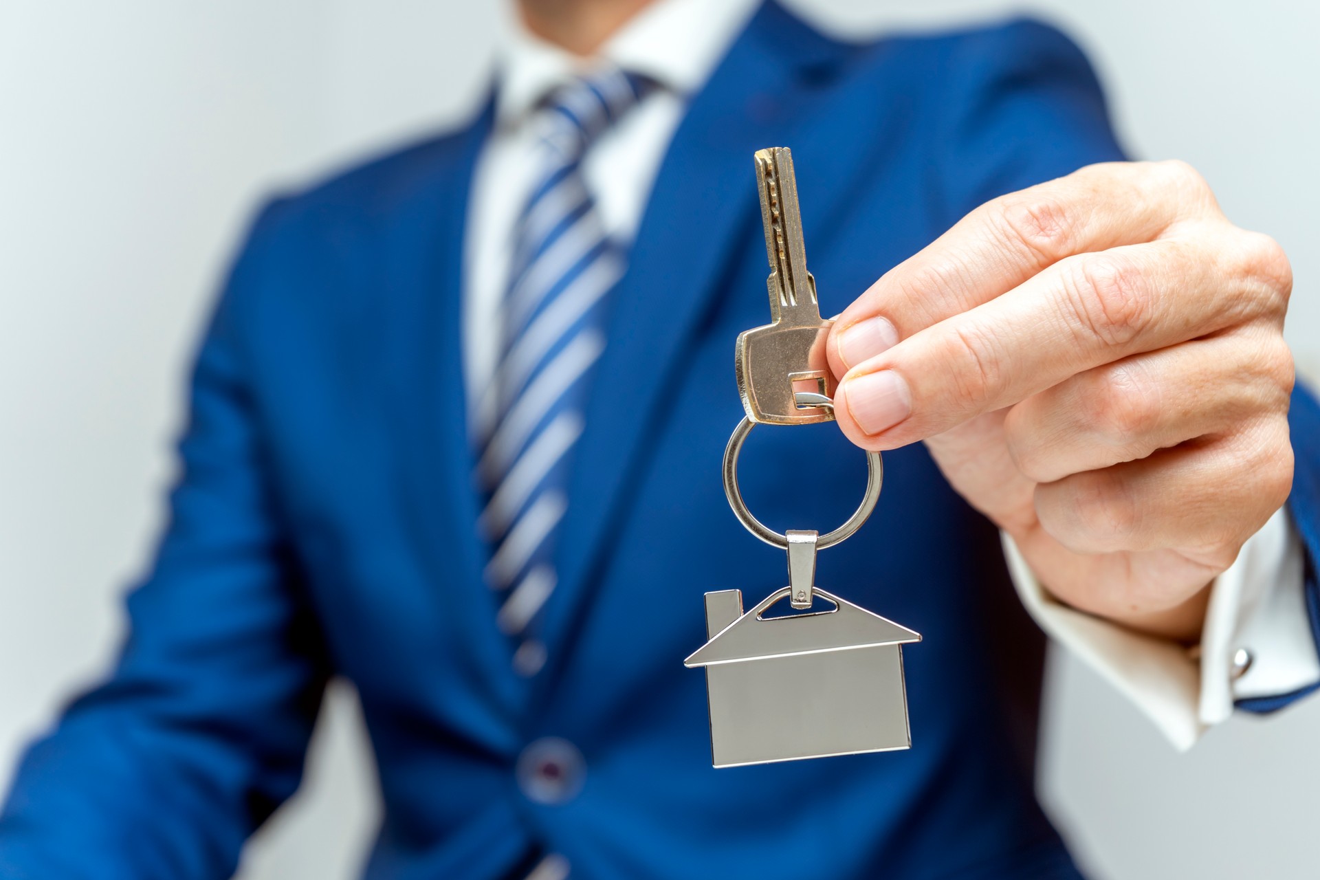 ELEGANT REAL ESTATE AGENT DELIVERING THE KEYS OF THE HOUSE TO THE NEW OWNER. HOME BUYING PROCESS AND SIGN THE MORTGAGE.